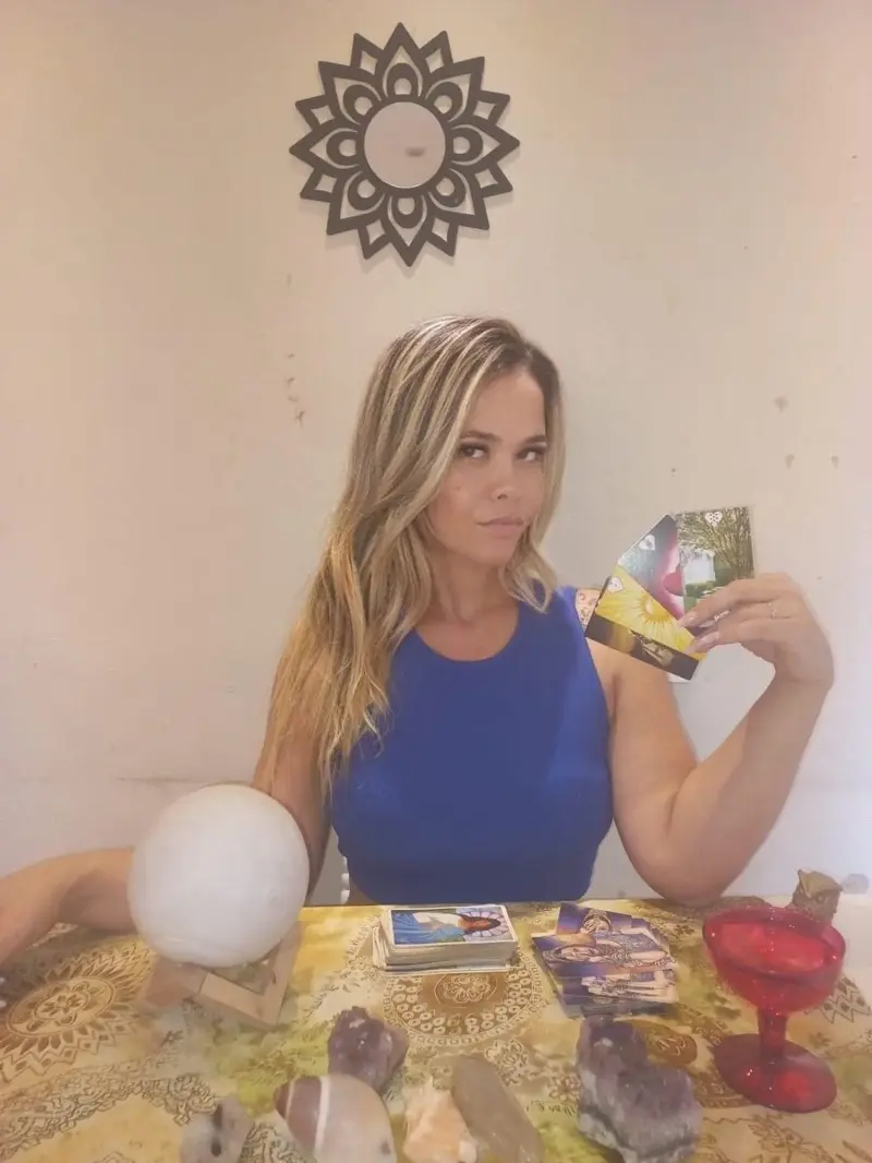 Andressa à mesa de atendimento com cartas e cristais